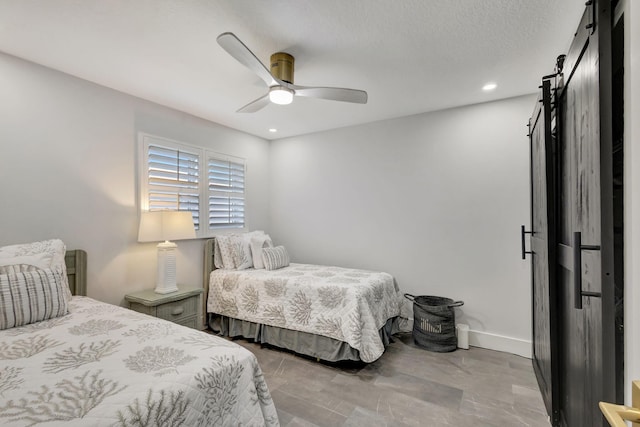 bedroom featuring ceiling fan and a barn door