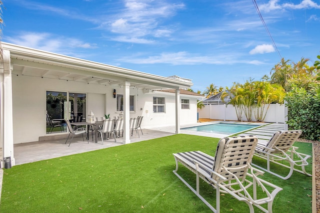 rear view of house featuring a yard, a fenced in pool, and a patio area