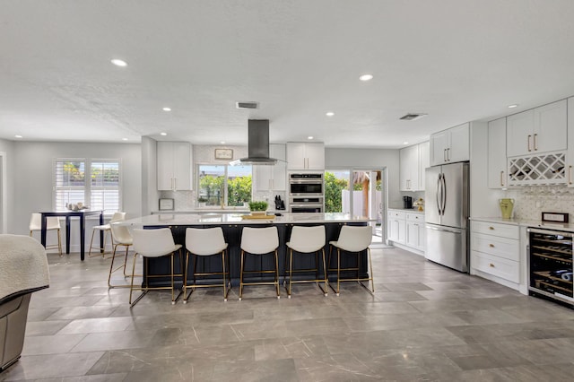 kitchen featuring island exhaust hood, appliances with stainless steel finishes, white cabinets, and beverage cooler