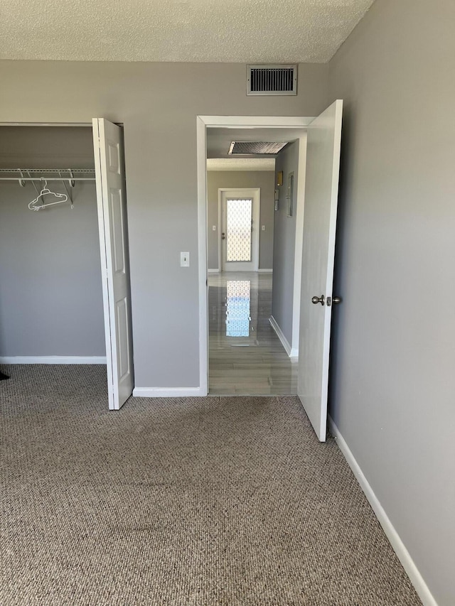 unfurnished bedroom with carpet, a textured ceiling, and a closet