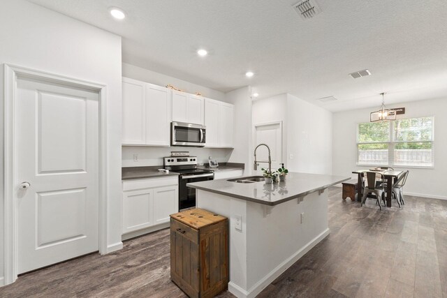 kitchen with white cabinetry, a center island with sink, stainless steel appliances, pendant lighting, and sink