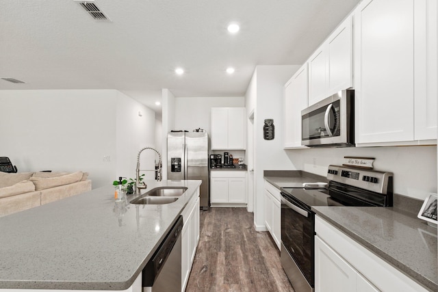 kitchen with appliances with stainless steel finishes, an island with sink, white cabinets, and sink