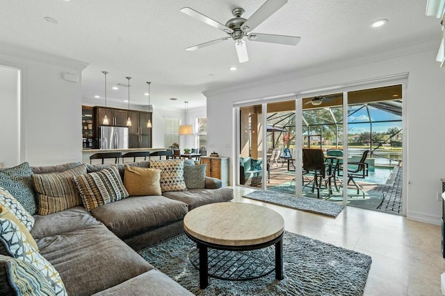 living room with a textured ceiling, ceiling fan, and ornamental molding