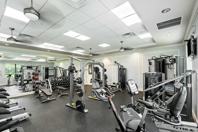 gym featuring ceiling fan, a drop ceiling, and crown molding