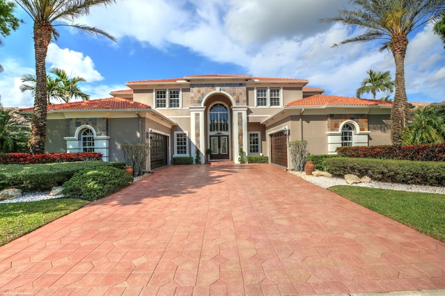 mediterranean / spanish-style house featuring a garage, decorative driveway, stucco siding, and french doors