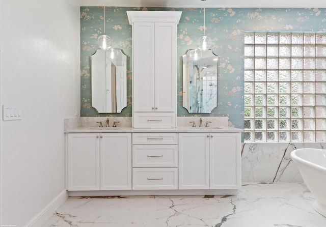 full bath with a freestanding tub, wallpapered walls, marble finish floor, and a sink