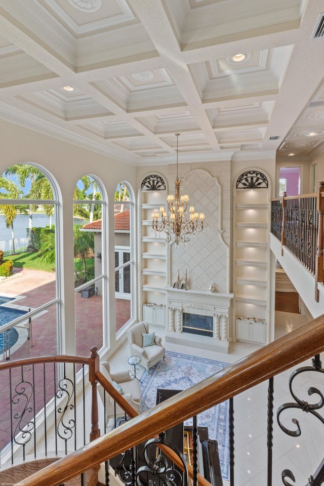 stairs featuring built in shelves, coffered ceiling, ornamental molding, tile patterned floors, and a notable chandelier