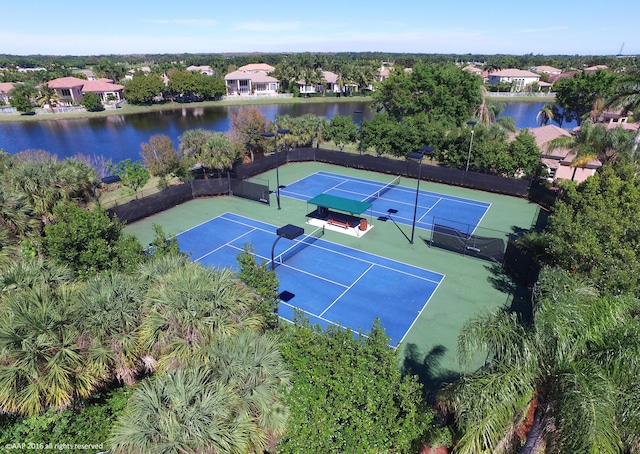 view of tennis court featuring a residential view, a water view, and fence