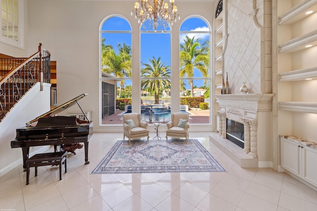 living area featuring a high ceiling, an inviting chandelier, a fireplace, light tile patterned floors, and stairs