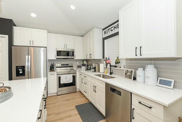 kitchen featuring tasteful backsplash, white cabinetry, sink, and stainless steel appliances