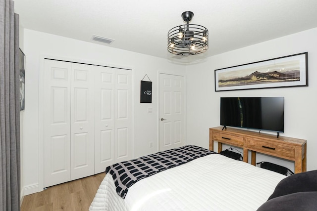 bedroom featuring light wood-type flooring, a closet, and a notable chandelier