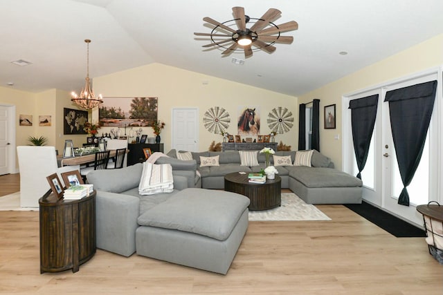 living room featuring ceiling fan with notable chandelier, light hardwood / wood-style floors, and lofted ceiling