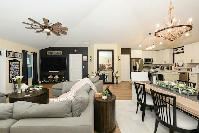 living room with ceiling fan with notable chandelier and vaulted ceiling