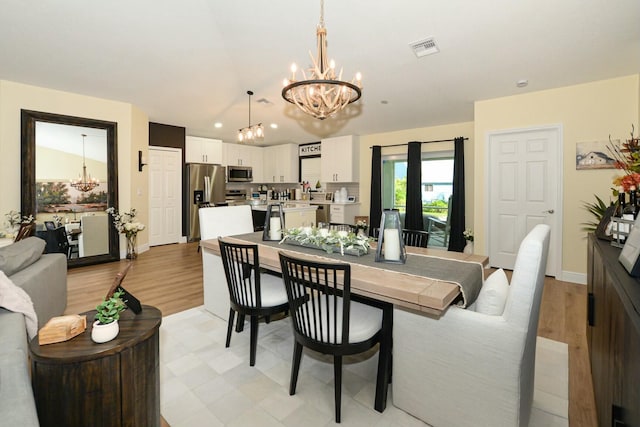 dining area featuring lofted ceiling, light hardwood / wood-style flooring, and an inviting chandelier