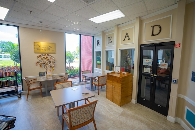 office with a drop ceiling, expansive windows, and french doors