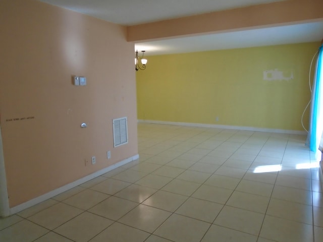 tiled empty room with an inviting chandelier