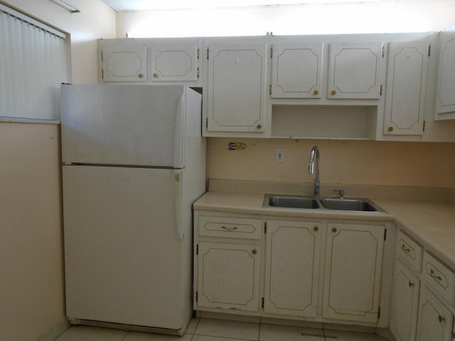 kitchen featuring white cabinets, white fridge, light tile patterned floors, and sink