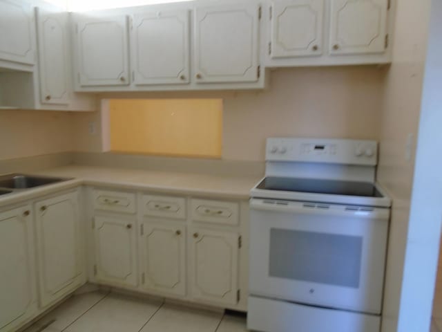 kitchen featuring white cabinets, white electric range oven, and light tile patterned floors