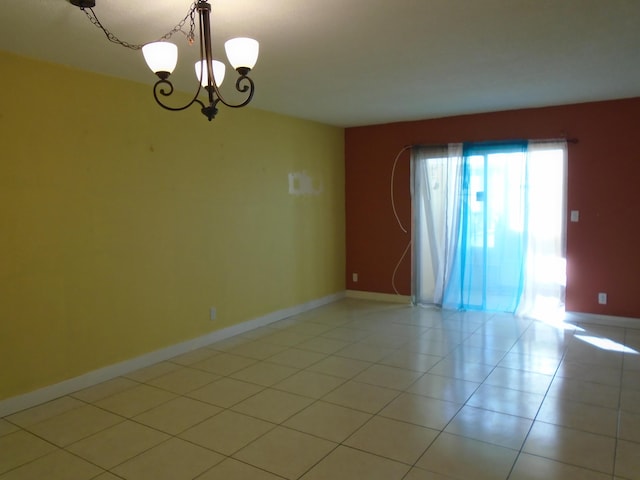 tiled spare room featuring an inviting chandelier