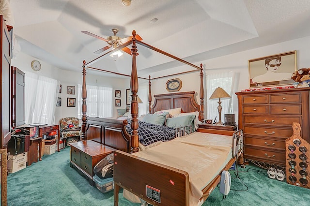 carpeted bedroom featuring ceiling fan, a textured ceiling, and a tray ceiling