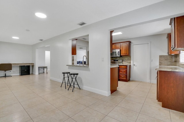 kitchen with a breakfast bar, light tile patterned floors, stainless steel appliances, and sink