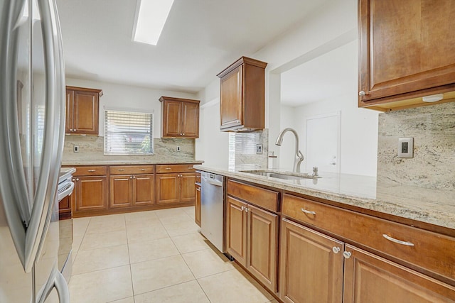 kitchen featuring light stone countertops, stainless steel appliances, tasteful backsplash, and sink