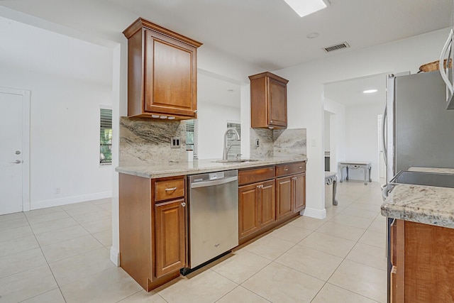 kitchen featuring decorative backsplash, appliances with stainless steel finishes, light stone countertops, sink, and light tile patterned floors