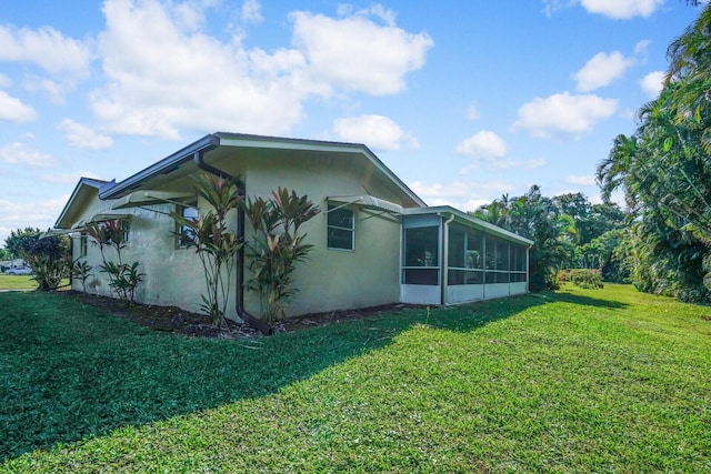 view of side of property featuring a lawn and a sunroom