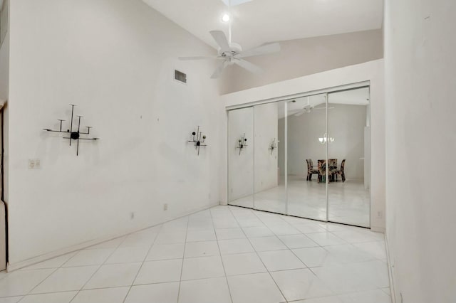 unfurnished room with light tile patterned floors, ceiling fan with notable chandelier, visible vents, and high vaulted ceiling