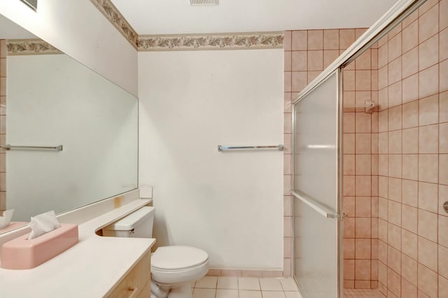 bathroom featuring toilet, vanity, tile patterned flooring, and a shower with shower door