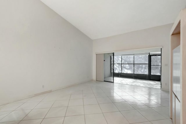 empty room with light tile patterned flooring and high vaulted ceiling