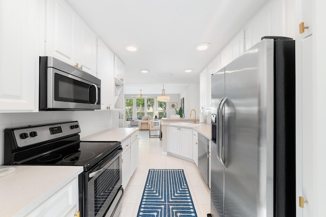 kitchen featuring sink, appliances with stainless steel finishes, decorative light fixtures, light tile patterned flooring, and white cabinetry