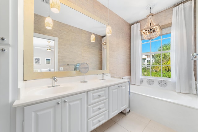 bathroom with vanity, ceiling fan with notable chandelier, a tub to relax in, and tile patterned floors