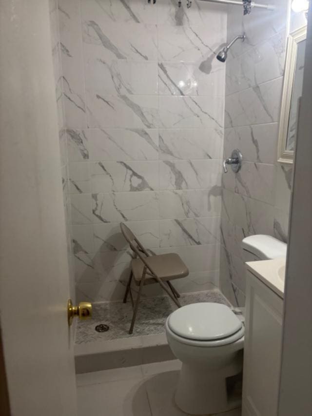 bathroom featuring tile patterned floors, vanity, toilet, and tiled shower