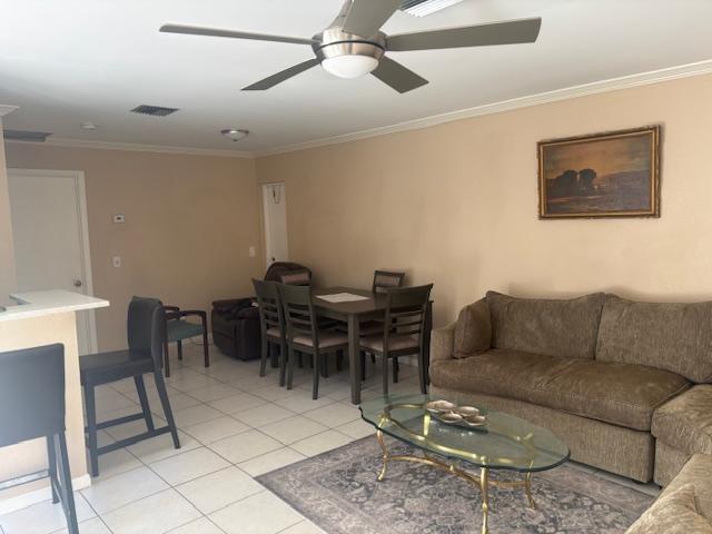 living room with ceiling fan, light tile patterned flooring, and ornamental molding