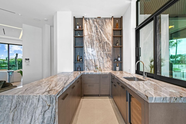 bar featuring built in shelves, light stone countertops, and sink