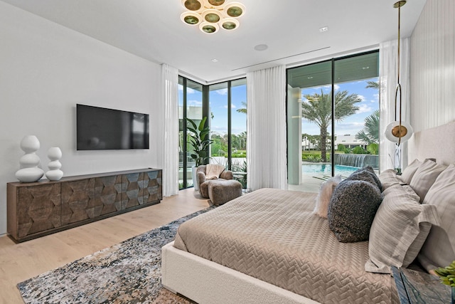 bedroom with hardwood / wood-style flooring, a wall of windows, and access to outside