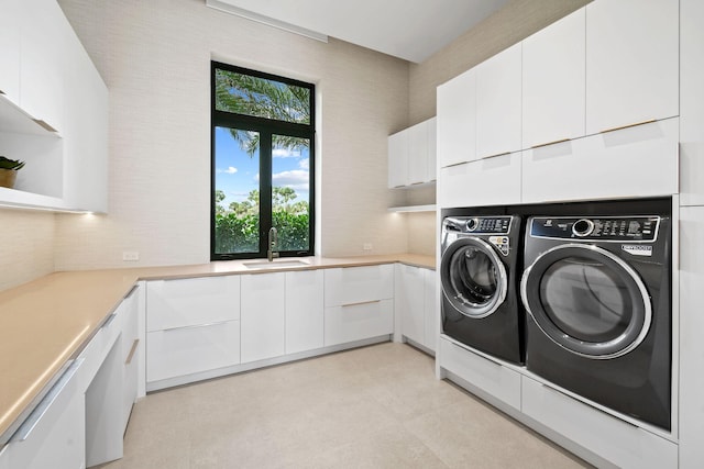 laundry area with a healthy amount of sunlight, cabinets, sink, and washing machine and dryer