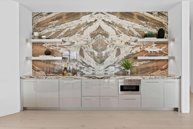 bar featuring light stone countertops, oven, and sink