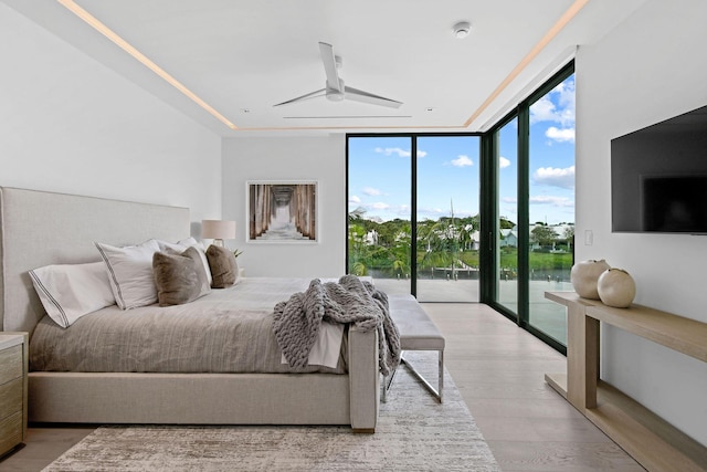 bedroom with access to exterior, wood-type flooring, expansive windows, and ceiling fan