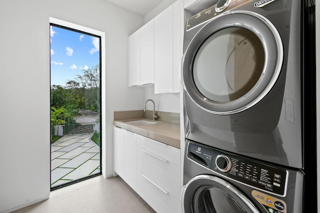 laundry area featuring cabinets, stacked washing maching and dryer, and sink