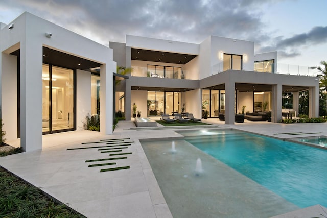 back of property with outdoor lounge area, a balcony, and a patio