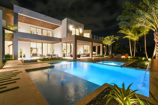 pool at twilight featuring a patio area, an in ground hot tub, and an outdoor hangout area