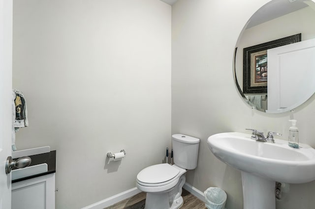 bathroom featuring toilet, wood-type flooring, and sink