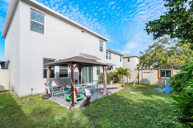 back of property with a gazebo, a patio area, and a lawn