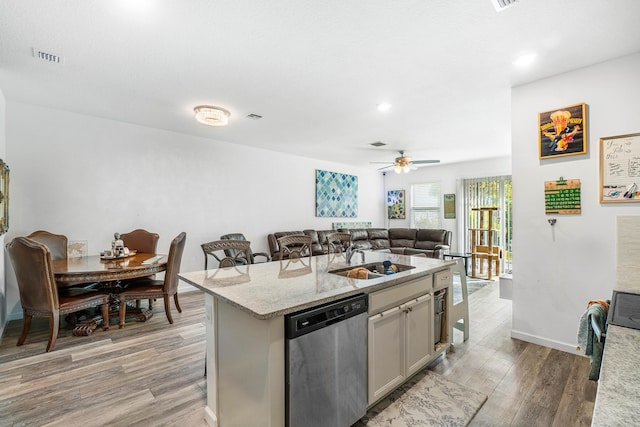 kitchen featuring dishwasher, light hardwood / wood-style flooring, gray cabinets, a kitchen island, and a kitchen bar