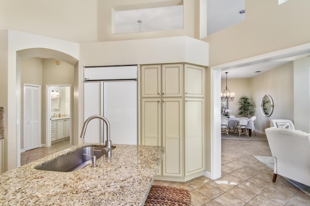 kitchen featuring white built in refrigerator, sink, light stone counters, and cream cabinets