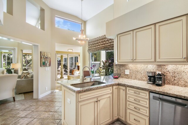 kitchen featuring appliances with stainless steel finishes, a towering ceiling, light stone countertops, a breakfast bar, and sink