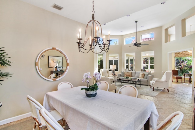 dining area with ceiling fan with notable chandelier, a wealth of natural light, and a towering ceiling