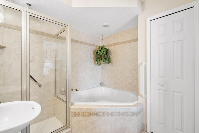 bathroom with a textured ceiling, sink, and shower with separate bathtub